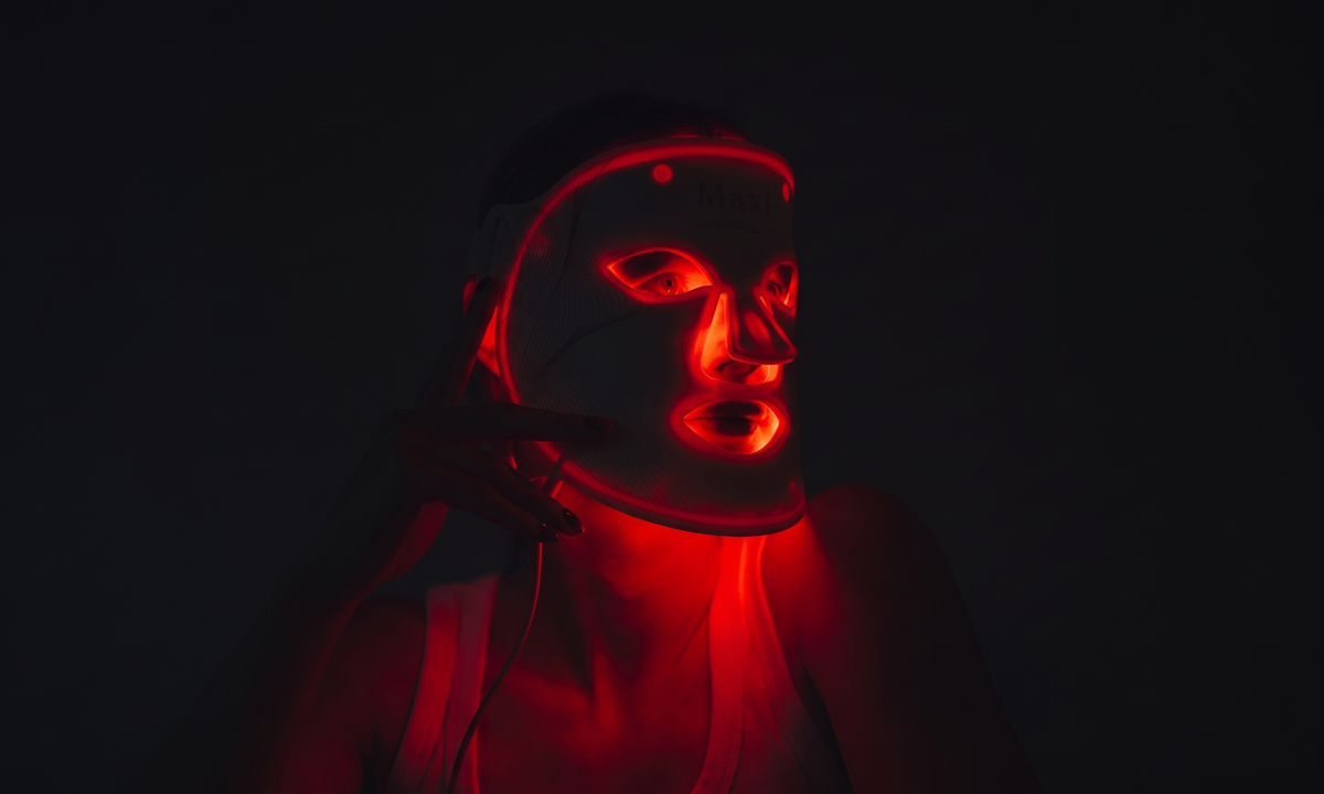 Vrouw gebruikt zwart LED-masker thuis